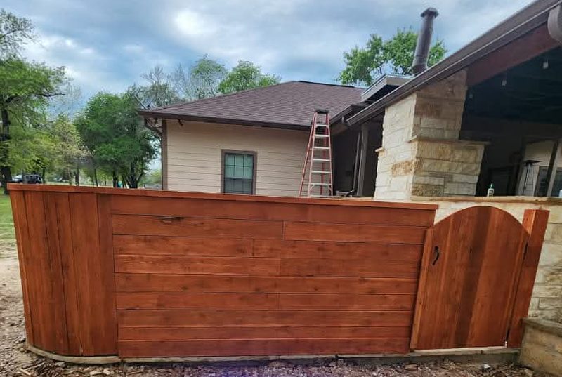Cerca de madera de tablas horizontales con puerta arqueada junto al patio