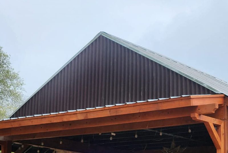 Pérgola de madera con el techo ampliado y el triángulo superior cerrado con lámina oscura